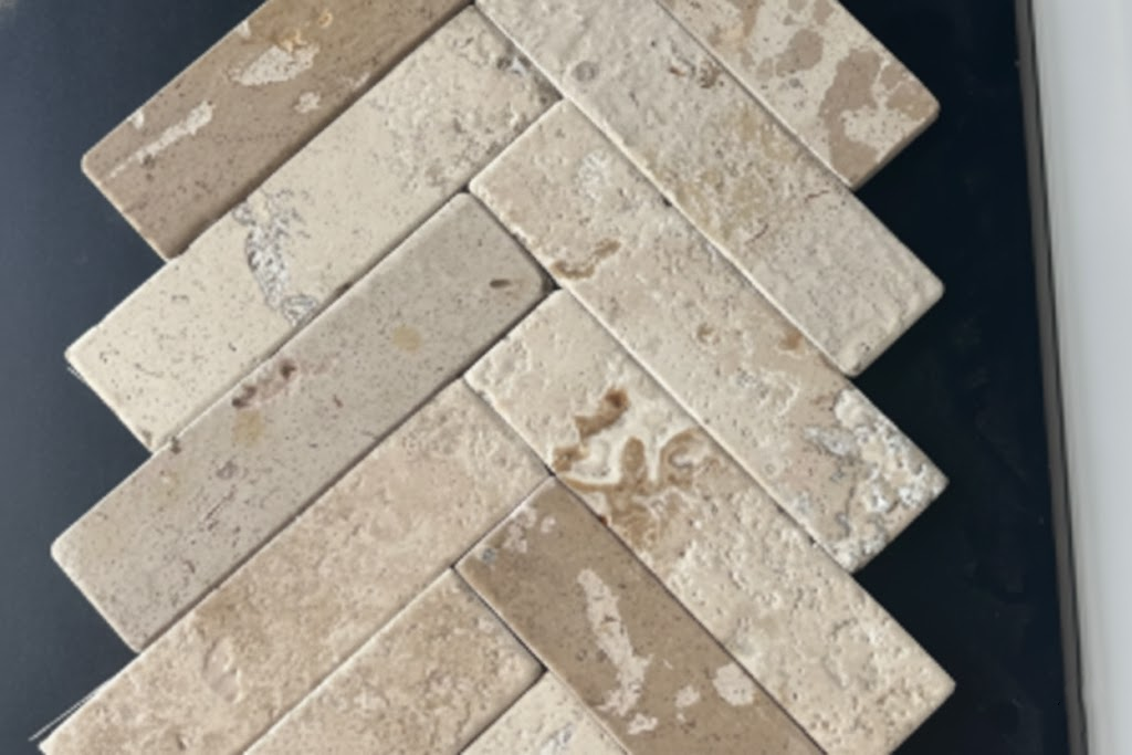 Herringbone-patterned natural limestone slab sample with beige and light brown organic stone texture.png